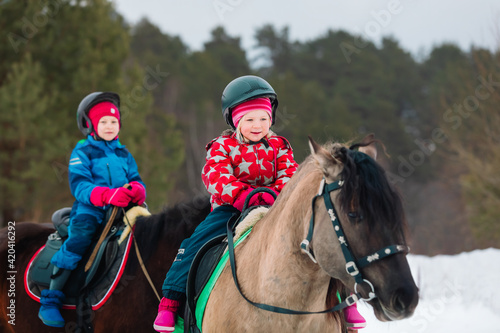 little girls on horse ride in winter nature