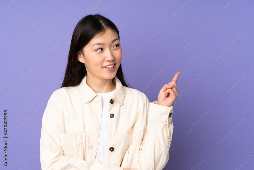 Young asian woman isolated on purple background pointing up a great idea Young asian woman isolated on purple background pointing up a great idea