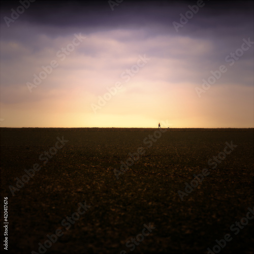 A landscape photo on a mountain at sunset with a walker and his dog on top of the ridge as an outline