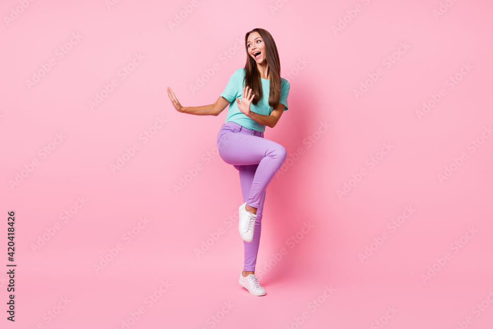 Full size photo of young happy smiling cheerful good mood woman wear violet pants dancing isolated on pink color background Full size photo of young happy smiling cheerful good mood woman wear violet pants dancing isolated on pink color background