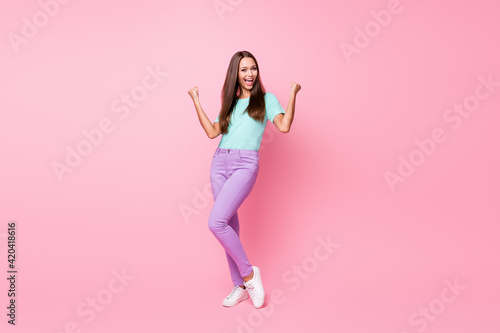 Full size photo of young happy attractive smiling cheerful woman dancing wear violet trousers isolated on pink color background