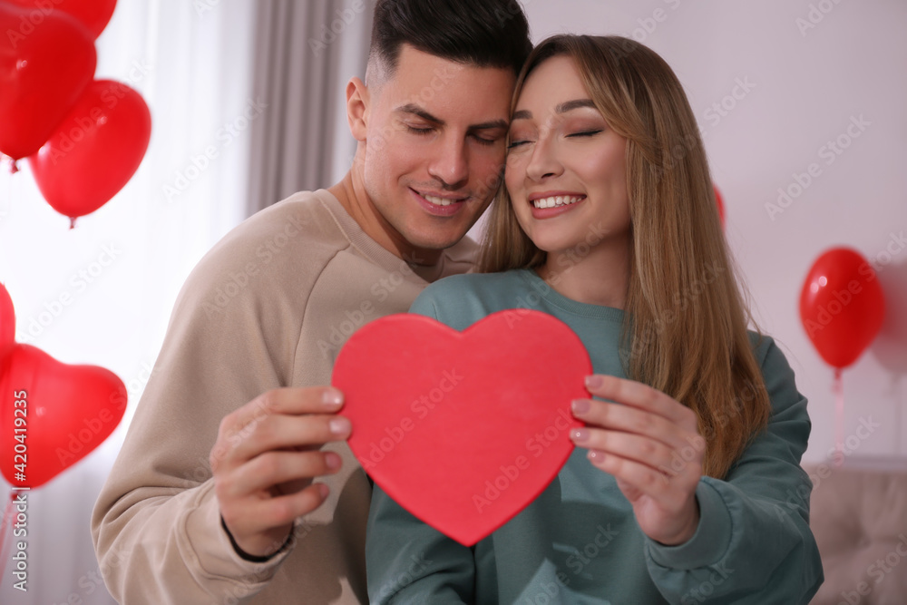 Lovely couple with gift in room. Valentine's day celebration Lovely couple with gift in room. Valentine's day celebration