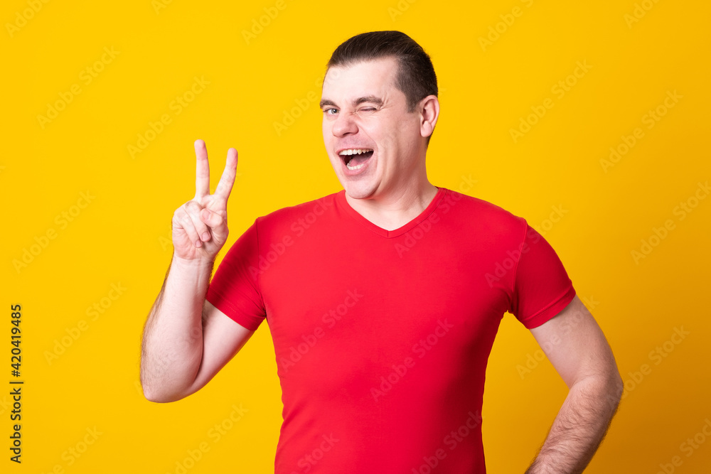 Young handsome man wearing casual shirt standing over isolated yellow background smiling with happy face winking at the camera doing victory sign with fingers. Number two. Young handsome man wearing casual shirt standing over isolated yellow background smiling with happy face winking at the camera doing victory sign with fingers. Number two.