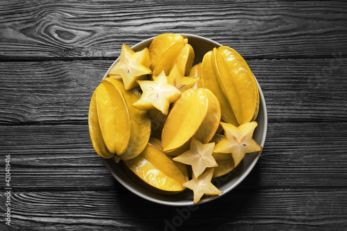 Delicious carambola fruits on black wooden table, top view