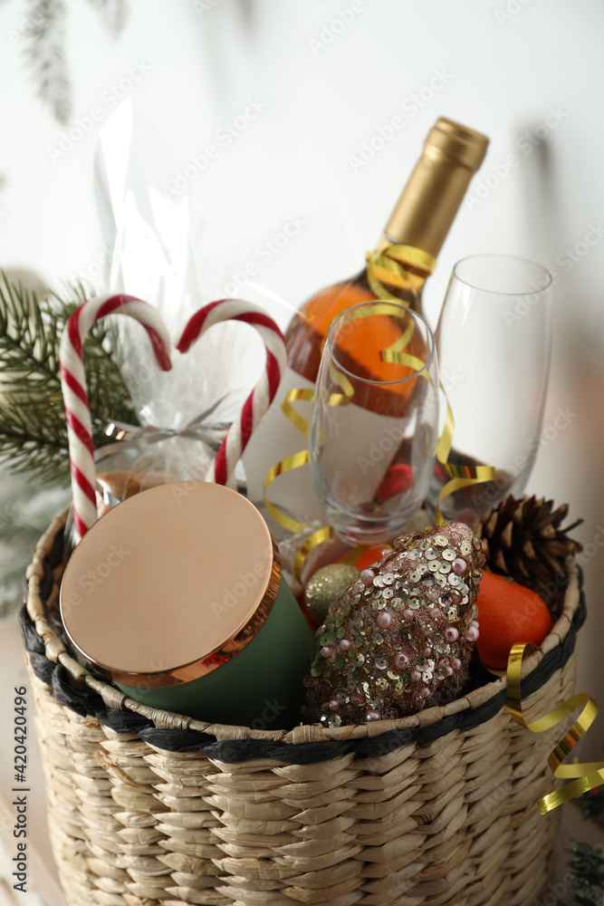 Wicker basket with gift set and Christmas decor near white wall Wicker basket with gift set and Christmas decor near white wall