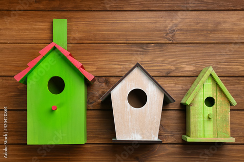 Three different bird houses on wooden background