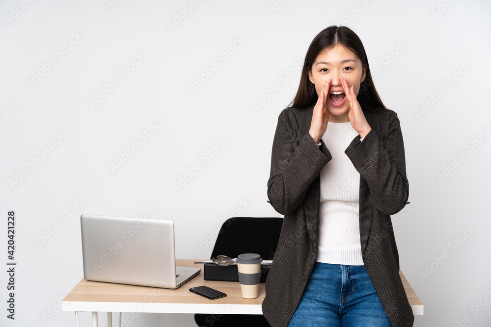 Business asian woman in her workplace isolated on white background shouting and announcing something Business asian woman in her workplace isolated on white background shouting and announcing something