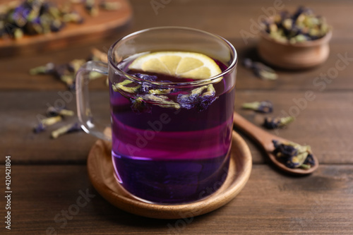 Glass mug of organic blue Anchan with lemon on wooden table. Herbal tea