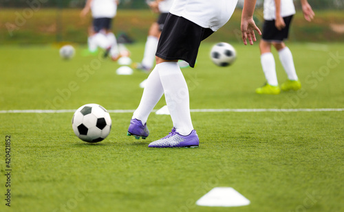 Soccer Player Kicking Ball on Training. Group of Footballers Improving Skills on Practice Venue. Soccer Boy in Purple Cleats and White Soccer Jersey Kit
