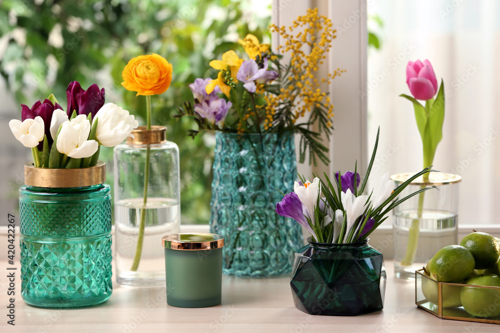 Different beautiful spring flowers and candle on window sill
