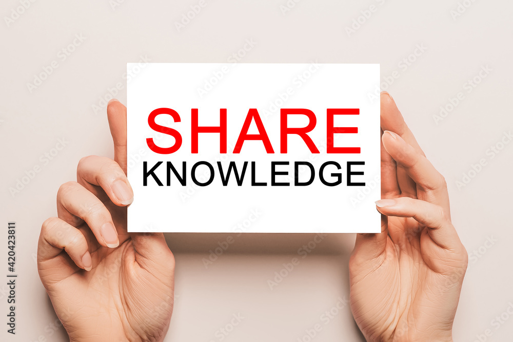 Female hands hold card paper with text SHARE KNOWLEDGE on a yellow background. Business and finance concept Female hands hold card paper with text SHARE KNOWLEDGE on a yellow background. Business and finance concept