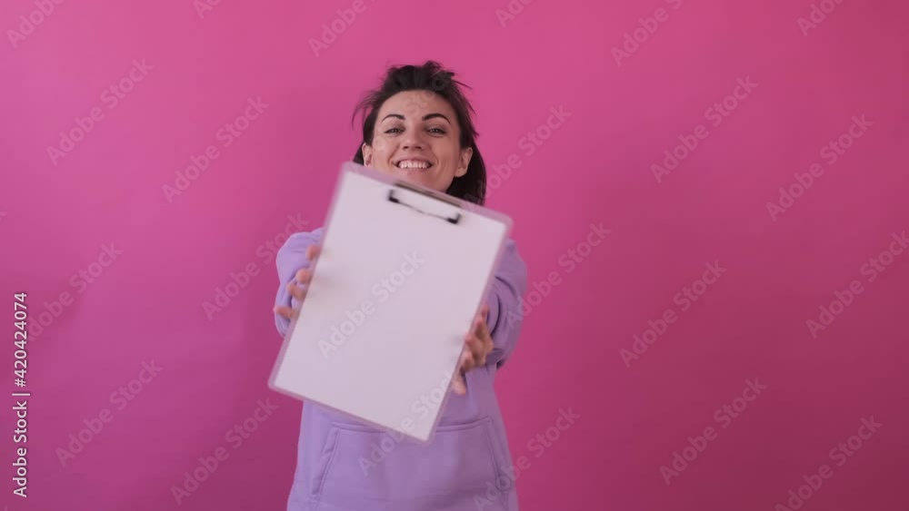 Caucasian woman isolated in casual purple shirt on pink background happy dancing with empty white sign board Caucasian woman isolated in casual purple shirt on pink background happy dancing with empty white sign board