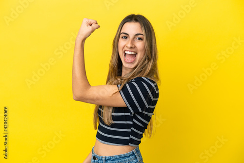 Young caucasian woman isolated on yellow background doing strong gesture © luismolinero