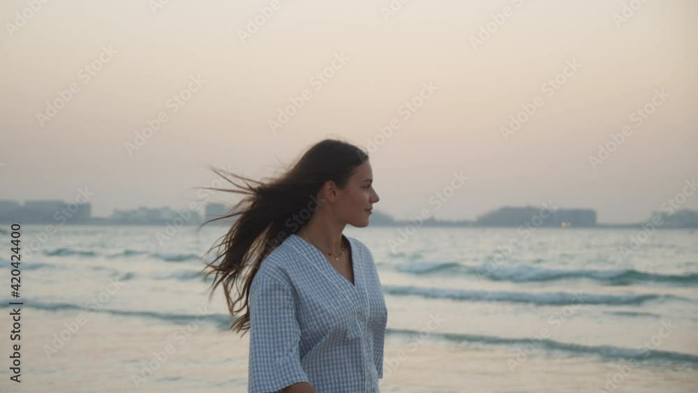 Close up view of attractive young brunette woman walking on the beach in Dubai