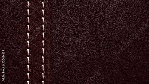 Background part of leather burgundy bag with white thread