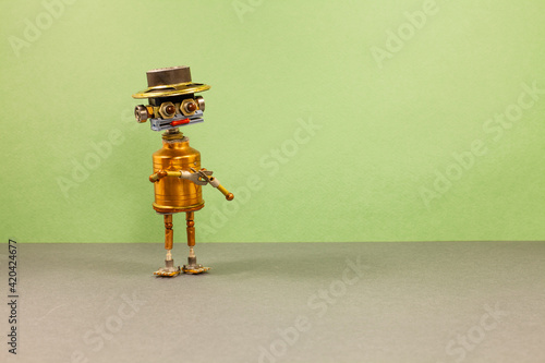 Funny copper mister robot with a funny hat on green gray background copy space