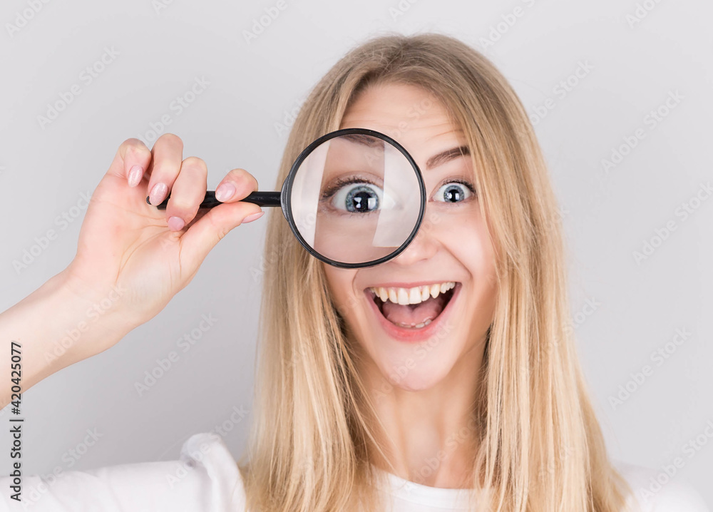 Close up portrait of cheerful beautiful girl looking through magnifying glass isolated on white background Close up portrait of cheerful beautiful girl looking through magnifying glass isolated on white background
