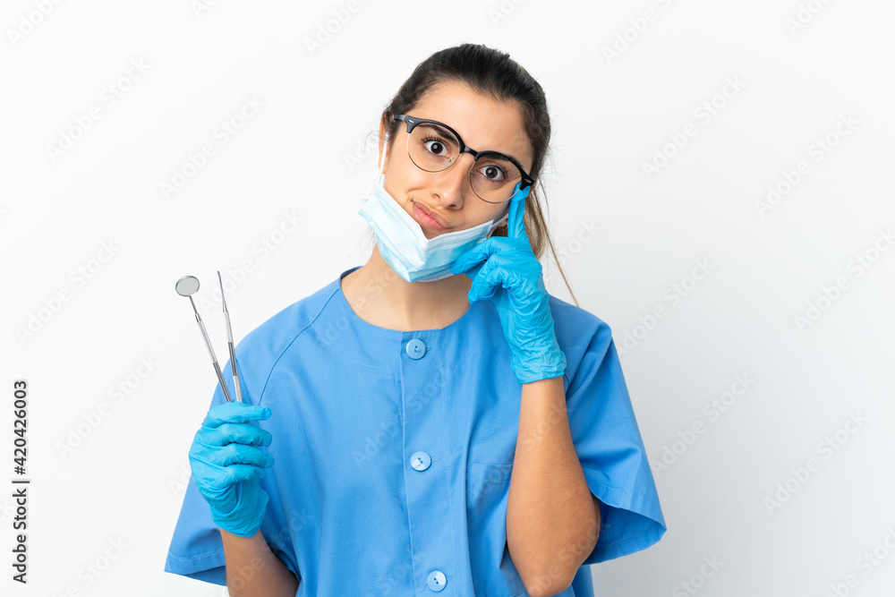 Young woman dentist holding tools isolated on white background thinking an idea Young woman dentist holding tools isolated on white background thinking an idea