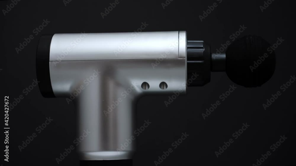 Massage percussion device rotating on black background. Suitable for advertising. Massage percussion device rotating on black background. Suitable for advertising.