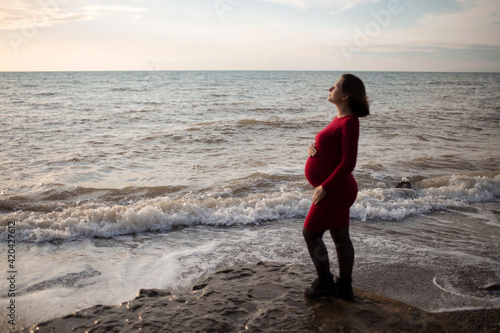 Stylish pregnant woman. Beautiful young pregnant woman enjoying the sunset. Pregnant tummy. The pleasure of pregnancy. Life style. Motherhood.Maternity. © Iana