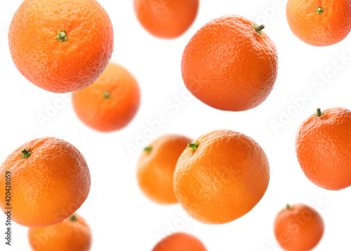 Fresh ripe tangerines falling on white background