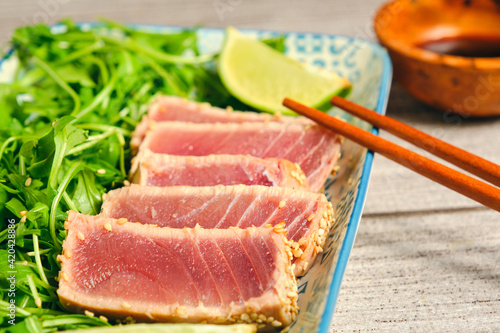 Tuna tataki with sesame with lemon and sticks to eat with arugula and soy sauce
