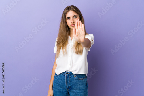 Young woman over isolated purple background making stop gesture