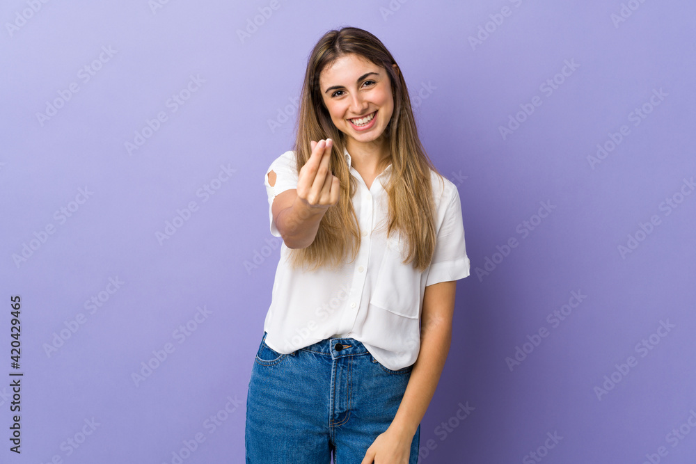 Young woman over isolated purple background making money gesture Young woman over isolated purple background making money gesture