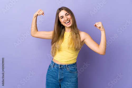 Young woman over isolated purple background doing strong gesture