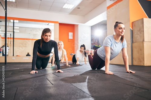 Motivated young women performing push-ups on gym floor