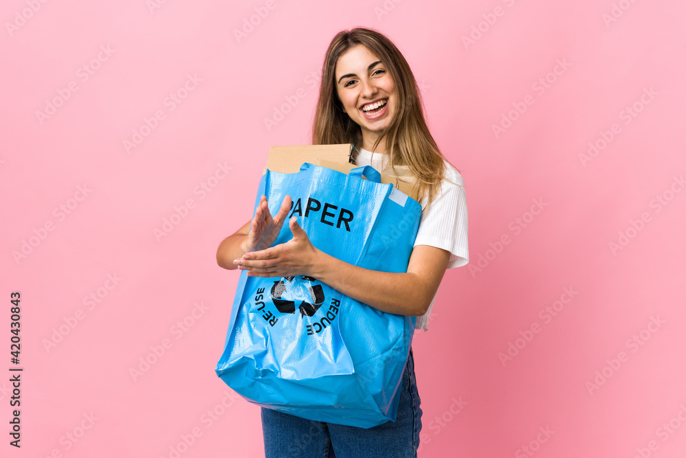 holding a recycling bag full of paper to recycle over isolated pink applauding holding a recycling bag full of paper to recycle over isolated pink applauding