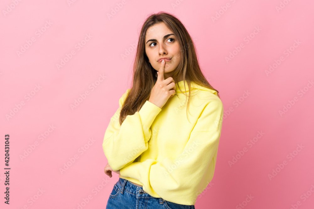 Young woman over isolated pink background having doubts while looking up Young woman over isolated pink background having doubts while looking up