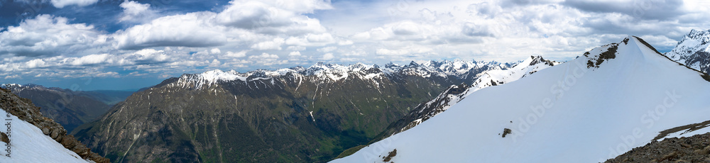 A wide panorama of the mountain peaks of the Caucasian ridge in sunny weather
