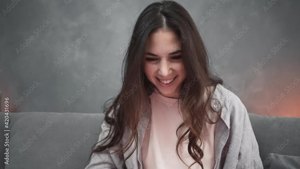 A happy woman is using her laptop sitting in the living room at home A happy woman is using her laptop sitting in the living room at home