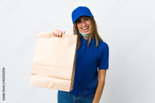 Food delivery woman and protecting from the coronavirus with a mask over isolated white background with happy expression