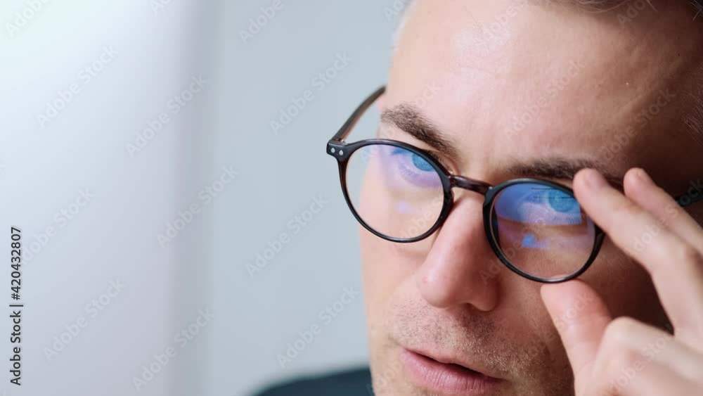 A close-up view of a concentrated businessman wearing glasses is working with his computer sitting in the office A close-up view of a concentrated businessman wearing glasses is working with his computer sitting in the office