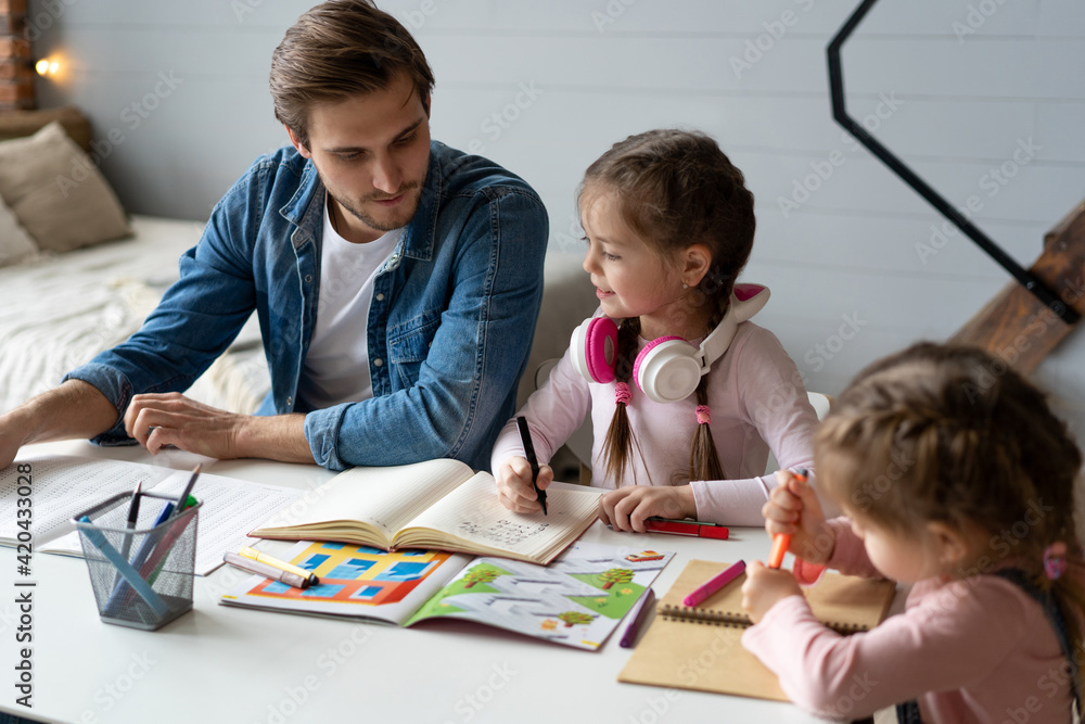 Fototapeta premium A father helping his little daughter to do her homework for the school