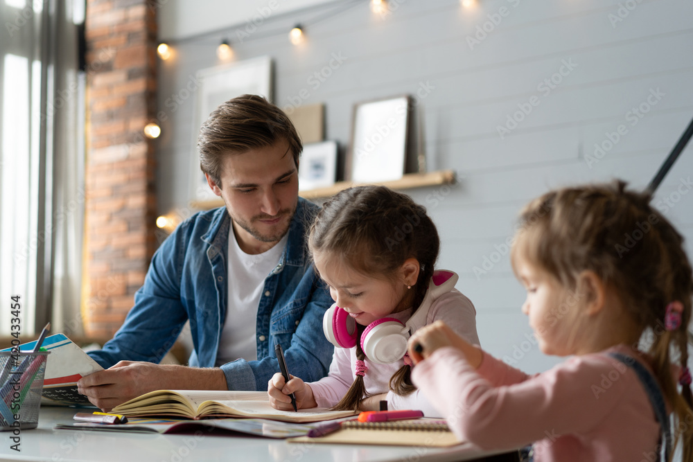 A father helping his little daughter to do her homework for the school A father helping his little daughter to do her homework for the school