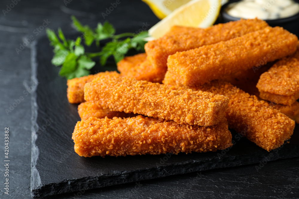 Fresh breaded fish fingers served on black table, closeup Fresh breaded fish fingers served on black table, closeup