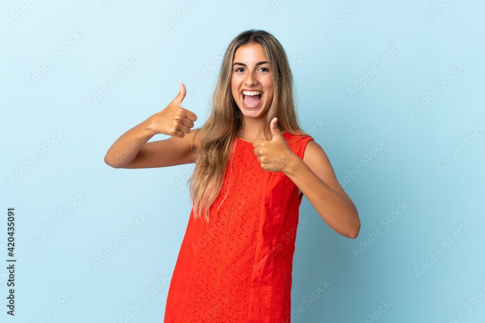 Fototapeta premium Young hispanic woman over isolated blue background giving a thumbs up gesture