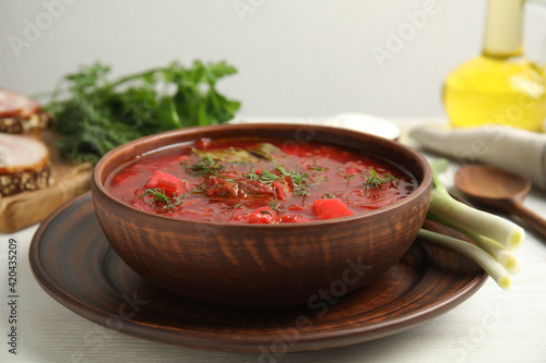 Stylish brown clay bowl with Ukrainian borsch served on white wooden table