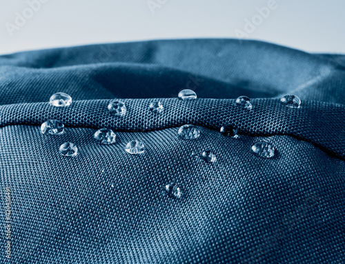 Water drops on waterproof membrane fabric. Detail view of texture of blue waterproof cloth.