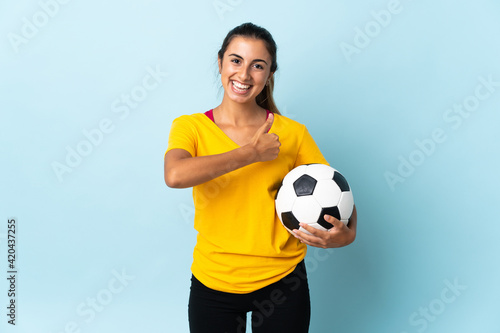 Young hispanic football player woman over isolated on blue background giving a thumbs up gesture © luismolinero