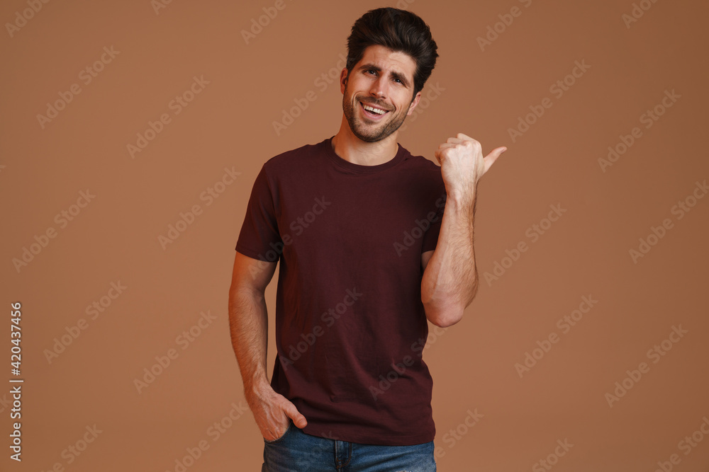 Joyful masculine man posing and pointing finger aside Joyful masculine man posing and pointing finger aside