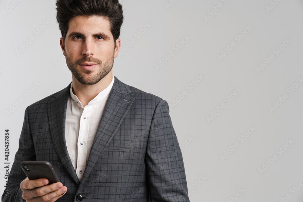 Confident young man in jacket posing and using mobile phone Confident young man in jacket posing and using mobile phone