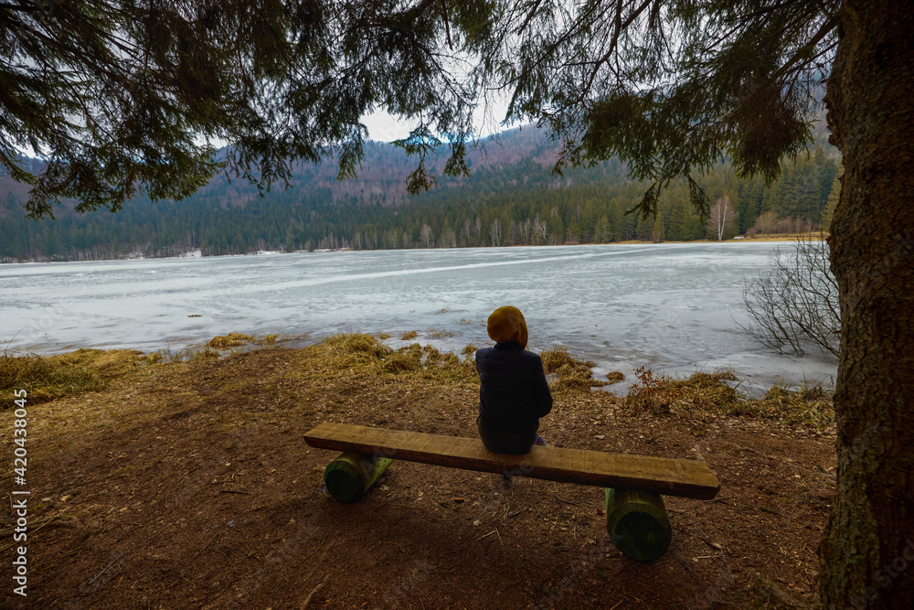 woman admiring the beautiful and volcanic lake Saint Ana in the winter time. Saint Ana volcanic lake in Tusnad Romania woman admiring the beautiful and volcanic lake Saint Ana in the winter time. Saint Ana volcanic lake in Tusnad Romania