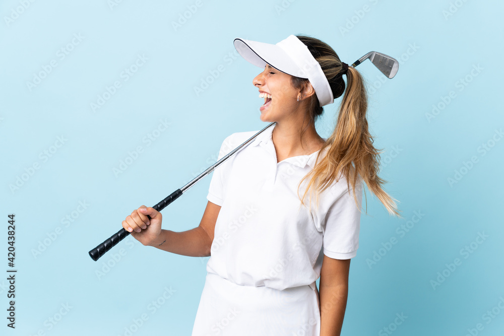 Young hispanic golfer woman over isolated blue wall laughing in lateral position Young hispanic golfer woman over isolated blue wall laughing in lateral position