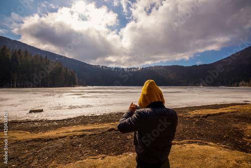 woman admiring the beautiful and volcanic lake Saint Ana in the winter time. Saint Ana volcanic lake in Tusnad Romania photo