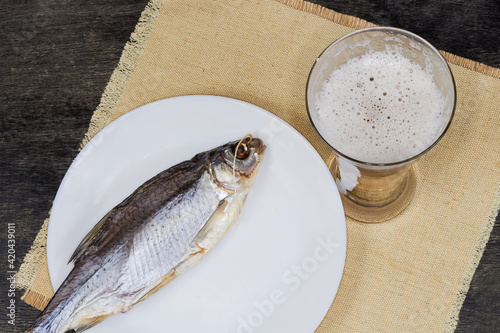 Top view of glass of beer against dried roach fish photo