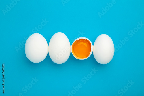 White eggs and egg yolk on the blue background. Easter concept.